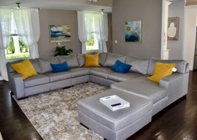 Spacious living room at Saint Patrick Palace with sectional sofa, accent pillows, and natural light in Davie, Florida