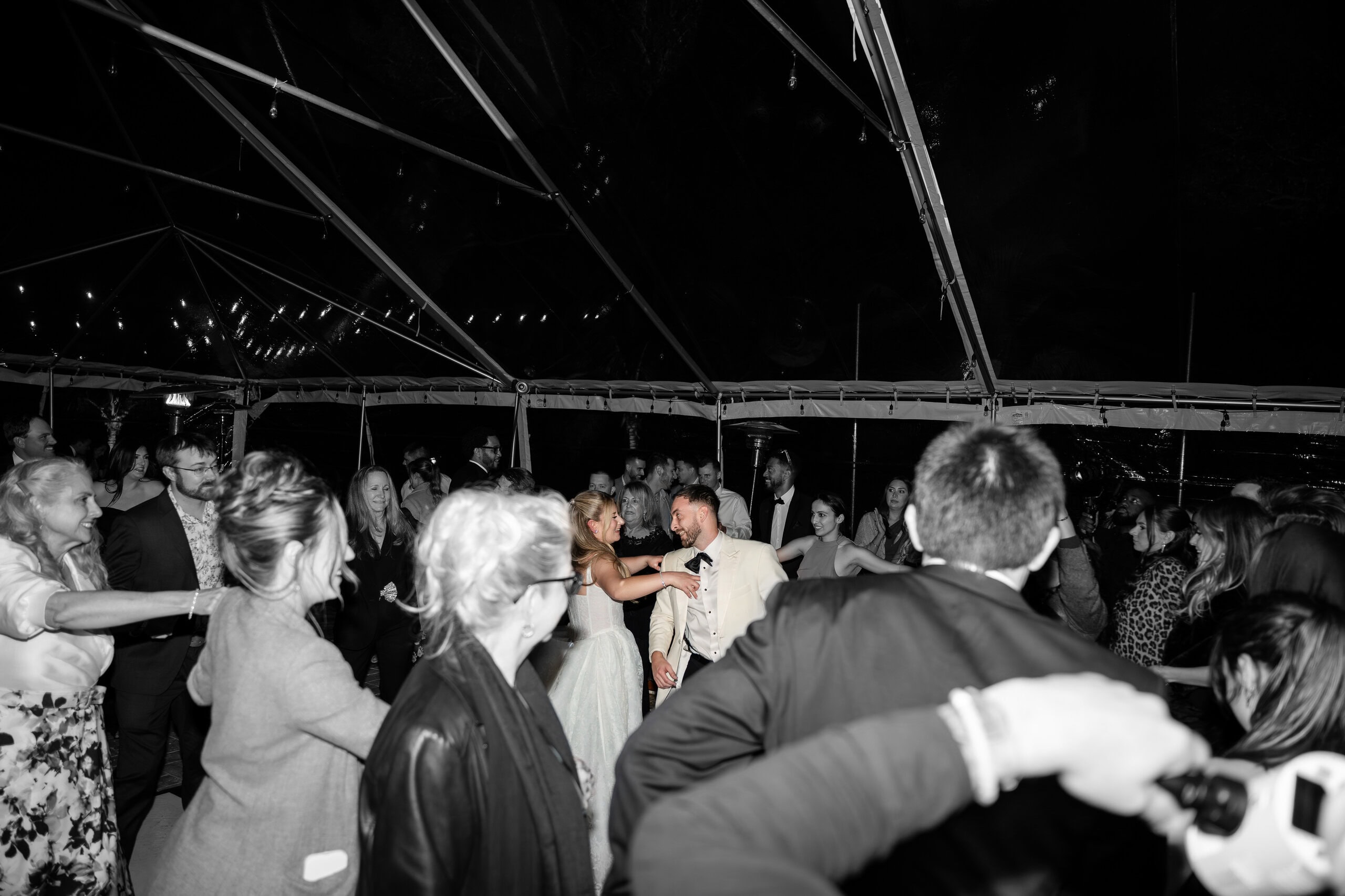 Bride, groom and guests dancing beneath a clear-top tent at a 100-guest South Florida wedding.