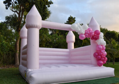 Pink bounce castle with balloon garland – perfect for outdoor weddings, birthdays, and party fun.