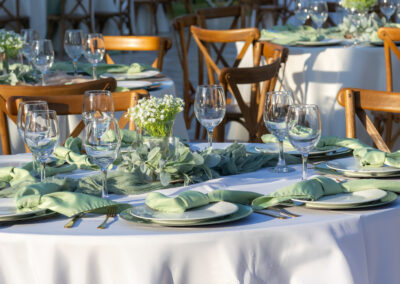 Elegant outdoor wedding with sage green accents, gold flatware, and fresh baby’s breath centerpieces.