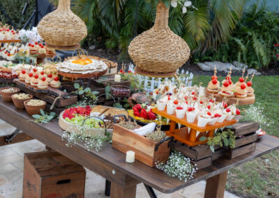 Rustic wedding grazing table with gourmet bites, white florals, and greenery for an elegant outdoor celebration.
