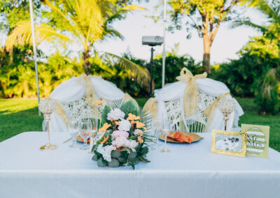Romantic outdoor sweetheart table with gold accents, florals, and elegant chair draping.
