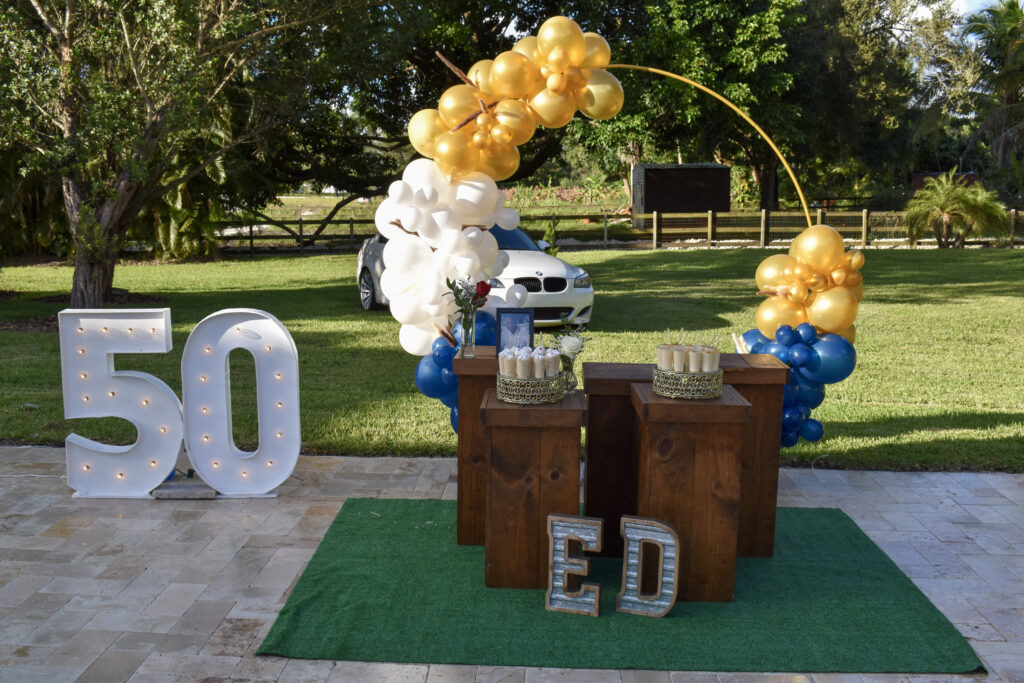 Elegant 50th birthday outdoor celebration with gold, navy, and white balloon decor.