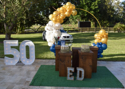 Elegant 50th birthday outdoor celebration with gold, navy, and white balloon decor.