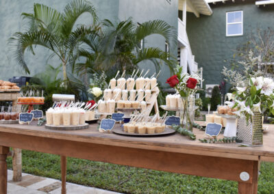 Elegant outdoor dessert table with tropical flowers and sweets for weddings, parties, and luxury events.