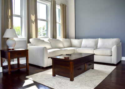 Bright sitting area at Saint Patrick Palace with cream sectional sofa, wood furniture, and natural light in Davie, Florida