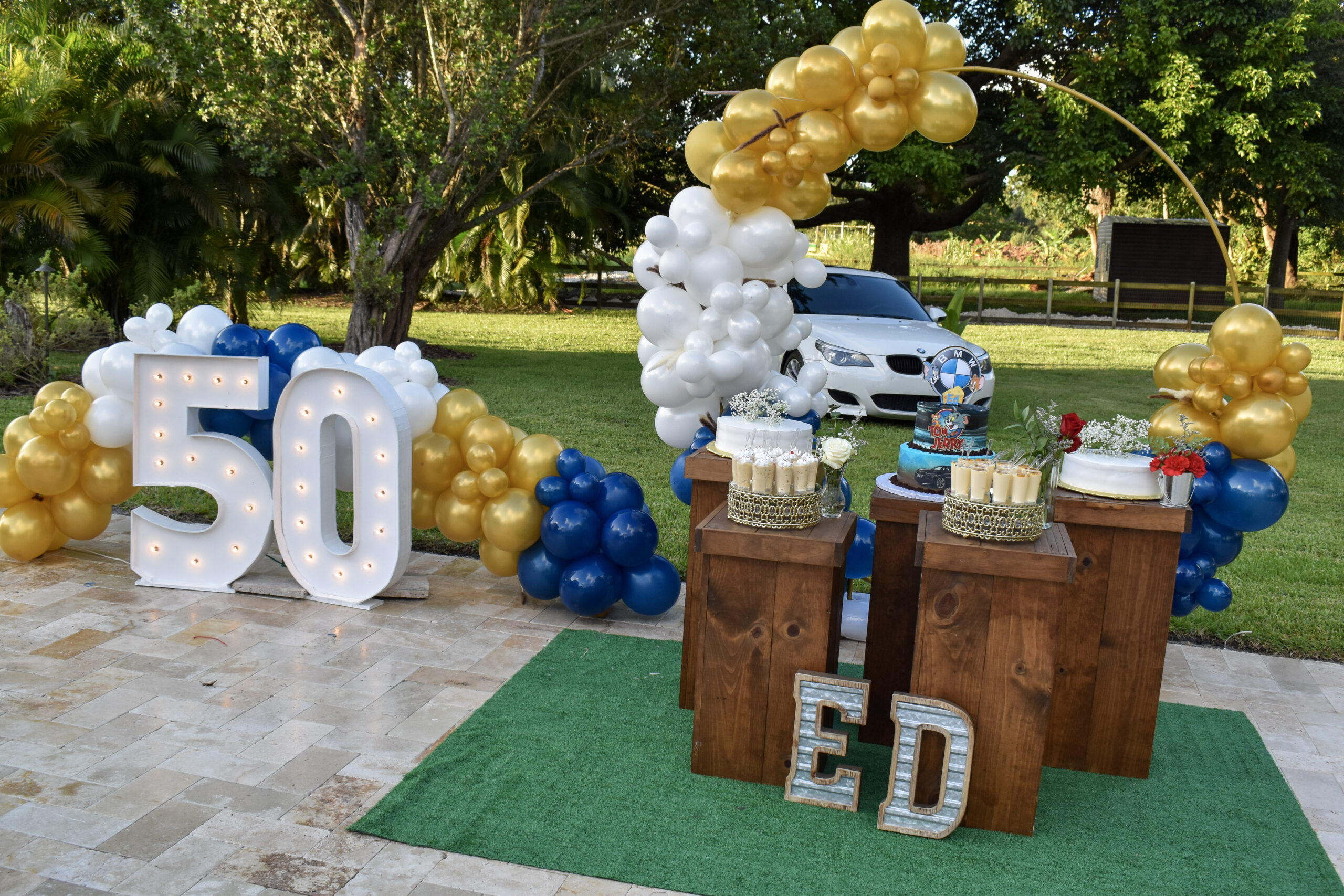 50th birthday party décor with marquee lights, gold and blue balloons, and dessert table setup.