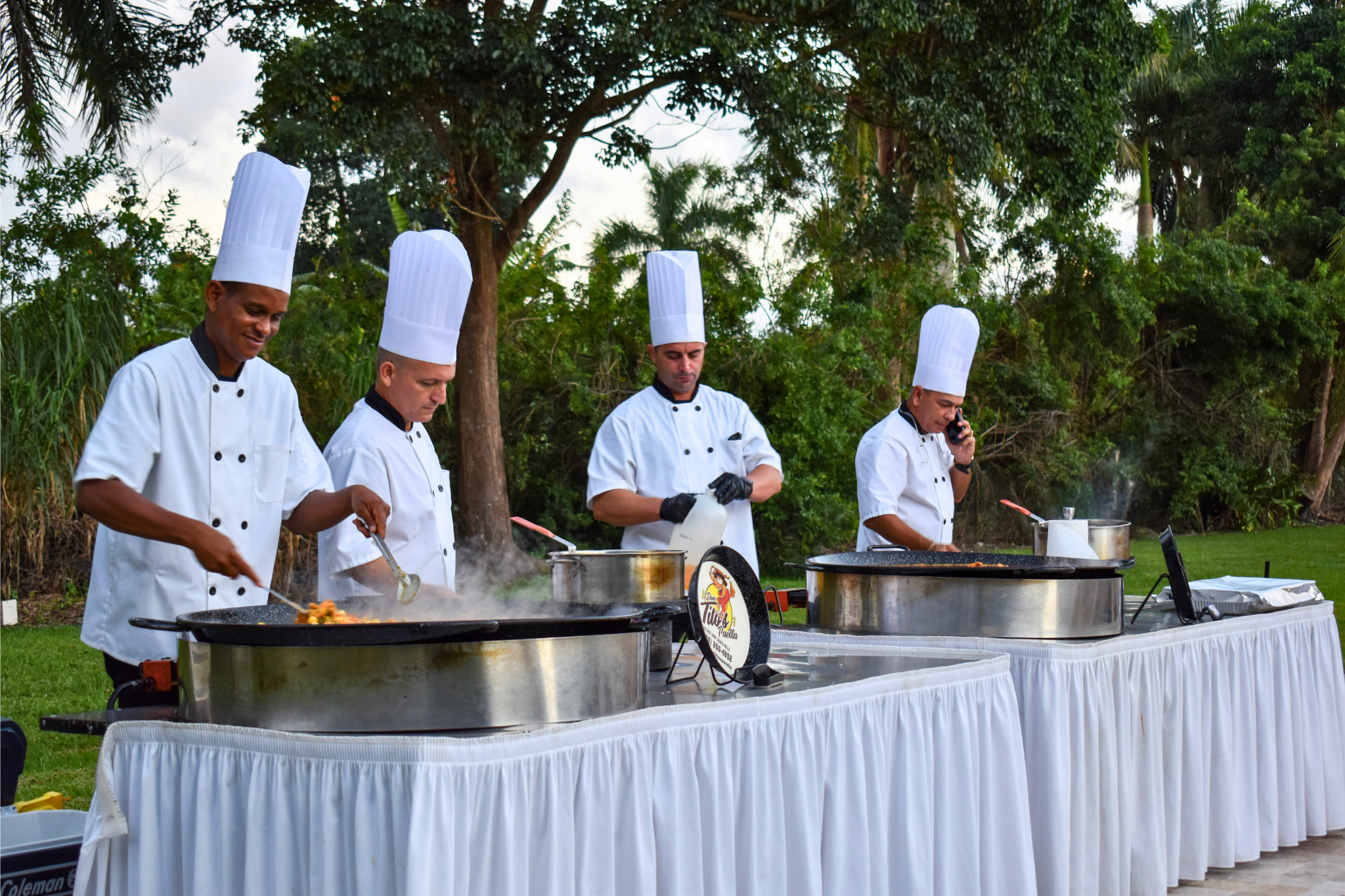 Chefs cooking paella outdoors for a 50th birthday party celebration in South Florida.