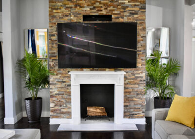 Fireplace and media wall at Saint Patrick Palace with stone accent wall, TV, and modern décor in Davie, Florida