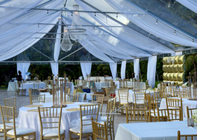 Elegant 60th birthday reception under clear-top tent with white drapery and gold chairs at Saint Patrick Palace Miami.