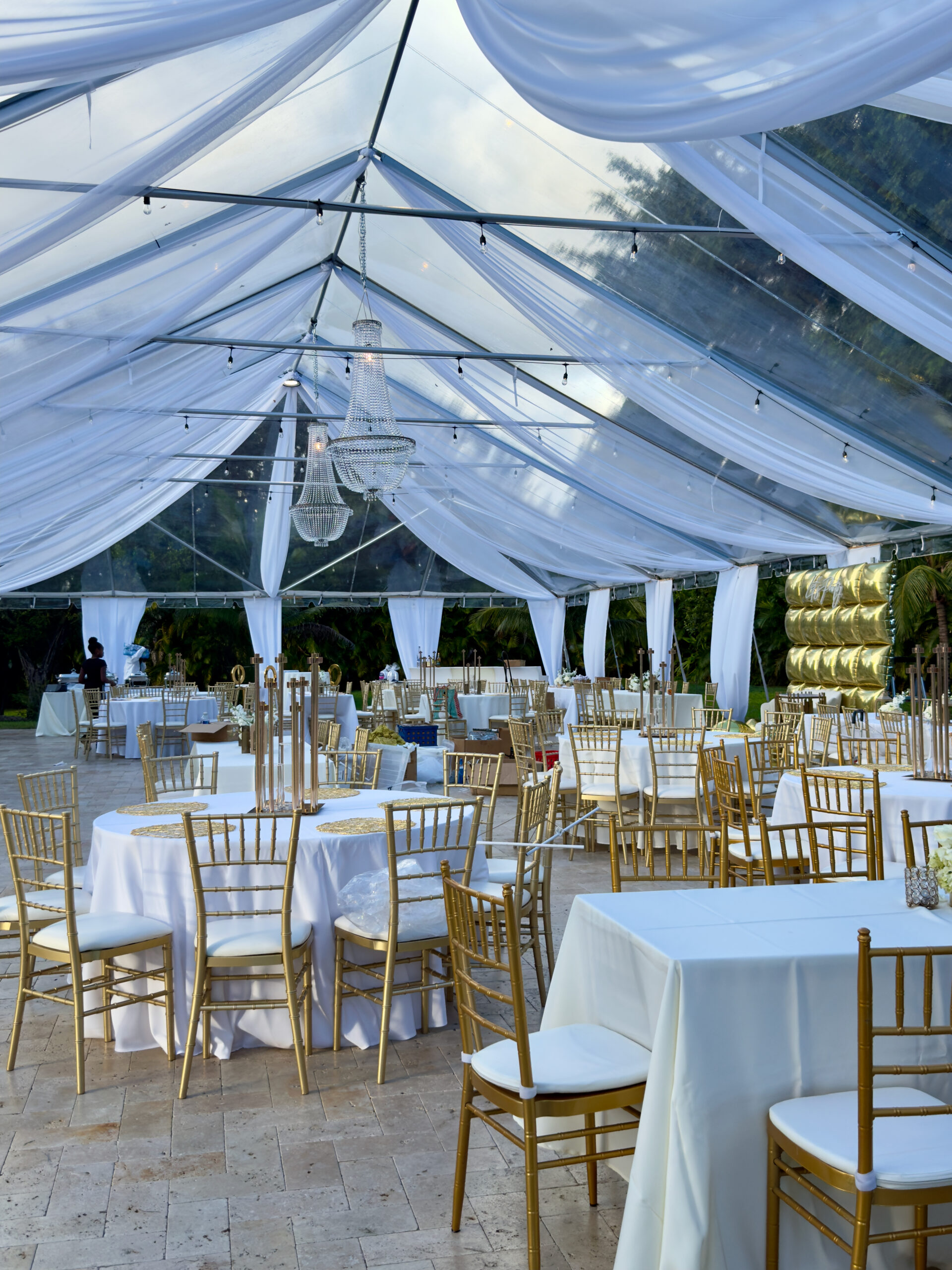 Elegant 60th birthday reception under clear-top tent with white drapery and gold chairs at Saint Patrick Palace Miami.