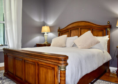 Elegant guest bedroom at Saint Patrick Palace with wood bedframe, soft bedding, and warm lighting in Davie, Florida
