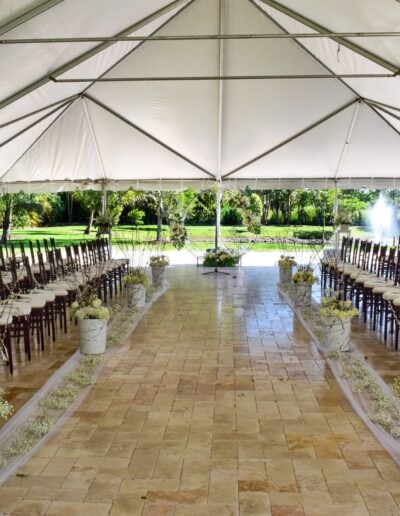 Tented outdoor wedding ceremony with elegant floral aisle decor at Saint Patrick Palace in Davie, Florida.