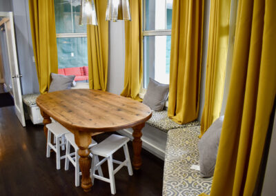 Cozy dining nook with rustic table, window seating, and golden drapes at Saint Patrick Palace