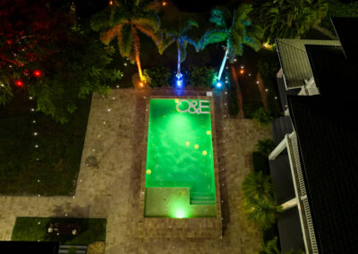 Luxury poolside wedding with glowing green LED lights, floating initials, and romantic string lights.
