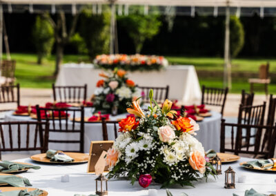 Vibrant wedding reception with bold florals and gold accents under a clear tent at Saint Patrick Palace.