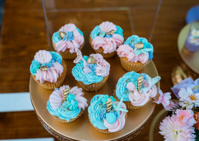 Mermaid cupcakes with pastel frosting, gold seashells, and tails—perfect for ocean-themed weddings or parties.