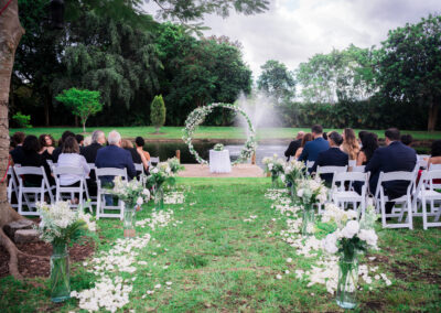 Lakeside wedding ceremony with circular floral arch at Saint Patrick Palace in Davie, FL.