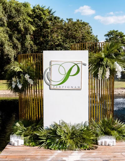 Elegant outdoor wedding backdrop with gold accents, greenery, and candles by the pond at Saint Patrick Palace.