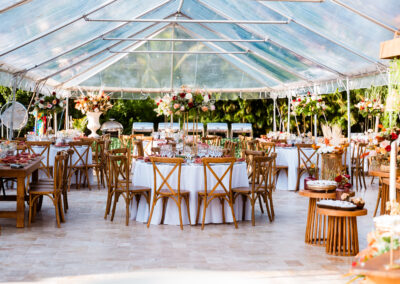 Chic outdoor wedding reception under a clear tent with lush florals at Saint Patrick Palace.