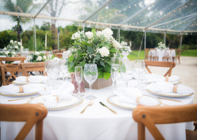 Elegant outdoor wedding table with white roses, gold chargers & romantic greenery.