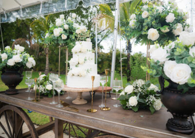 Elegant white wedding cake with greenery & roses, perfect for a luxury outdoor reception display.