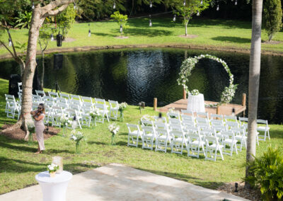 Romantic lakeside wedding with white floral arch & serene waterfront backdrop.