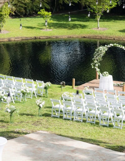 Romantic lakeside wedding with white floral arch & serene waterfront backdrop.