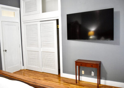 Bedroom with TV, hardwood floors, and closet at Saint Patrick Palace Davie