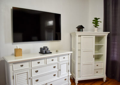 Guest room with flat-screen TV and elegant white storage furniture at Saint Patrick Palace