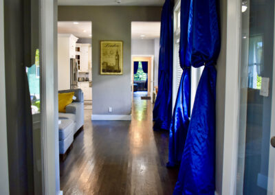Elegant hallway at Saint Patrick Palace with blue drapes, hardwood floors, and open flow design in Davie, Florida