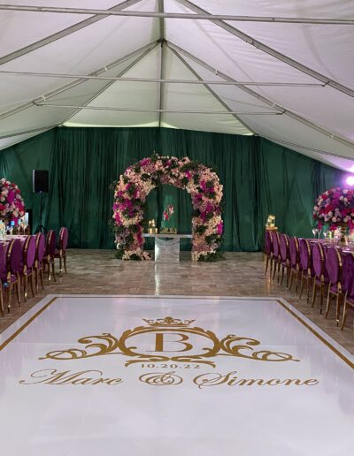 Elegant tented wedding with custom dance floor, lush florals, and luxe purple-and-gold décor at Saint Patrick Palace.