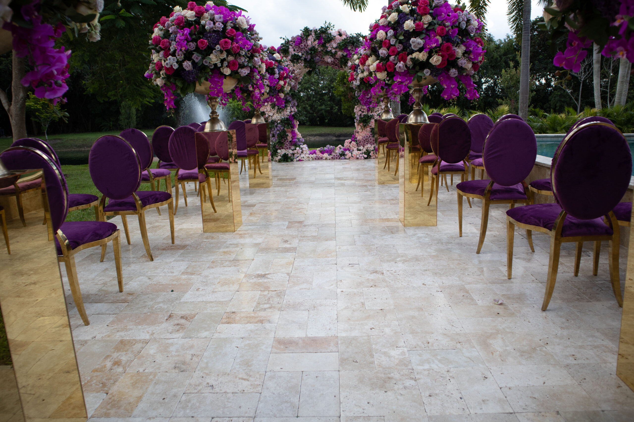 Glamorous outdoor wedding ceremony with vibrant floral arch, gold chairs, and mirrored pedestals at Saint Patrick Palace.