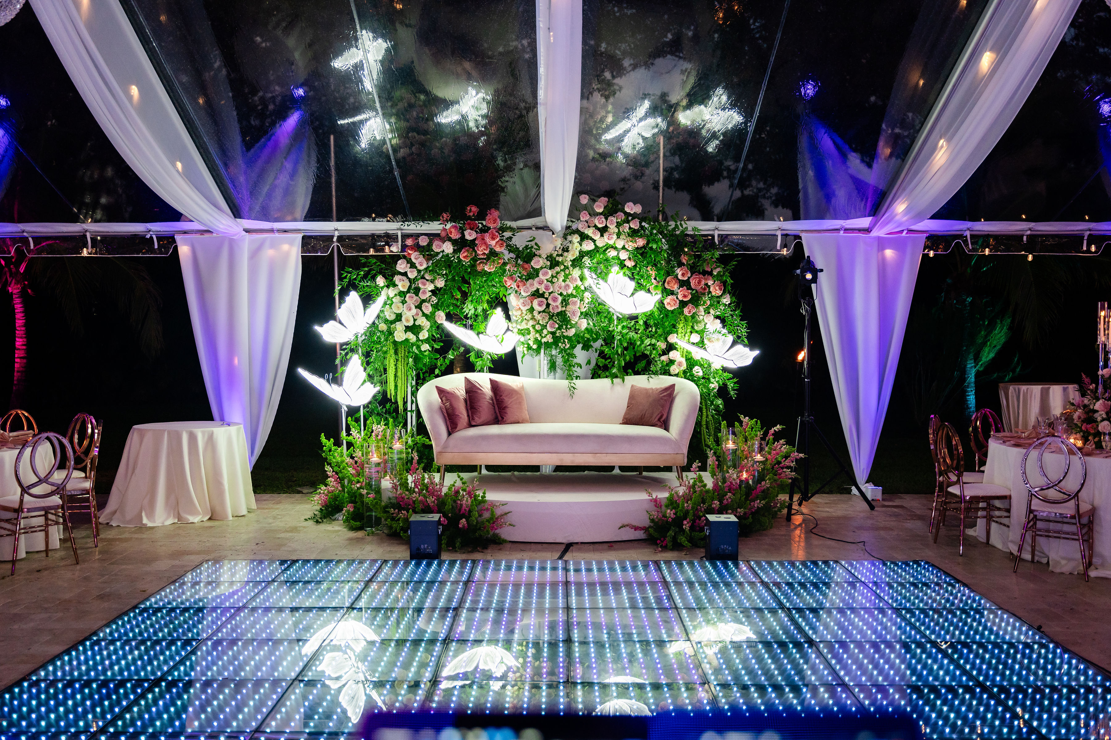 Rose gold quinceañera celebration on a glowing LED dance floor under a clear tent at Saint Patrick Palace estate venue.