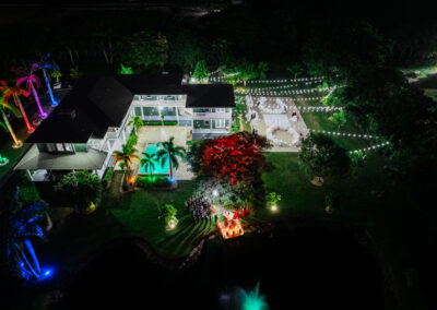 Vibrant nighttime wedding at Saint Patrick Palace with colorful uplighting, string lights, and waterfront elegance.