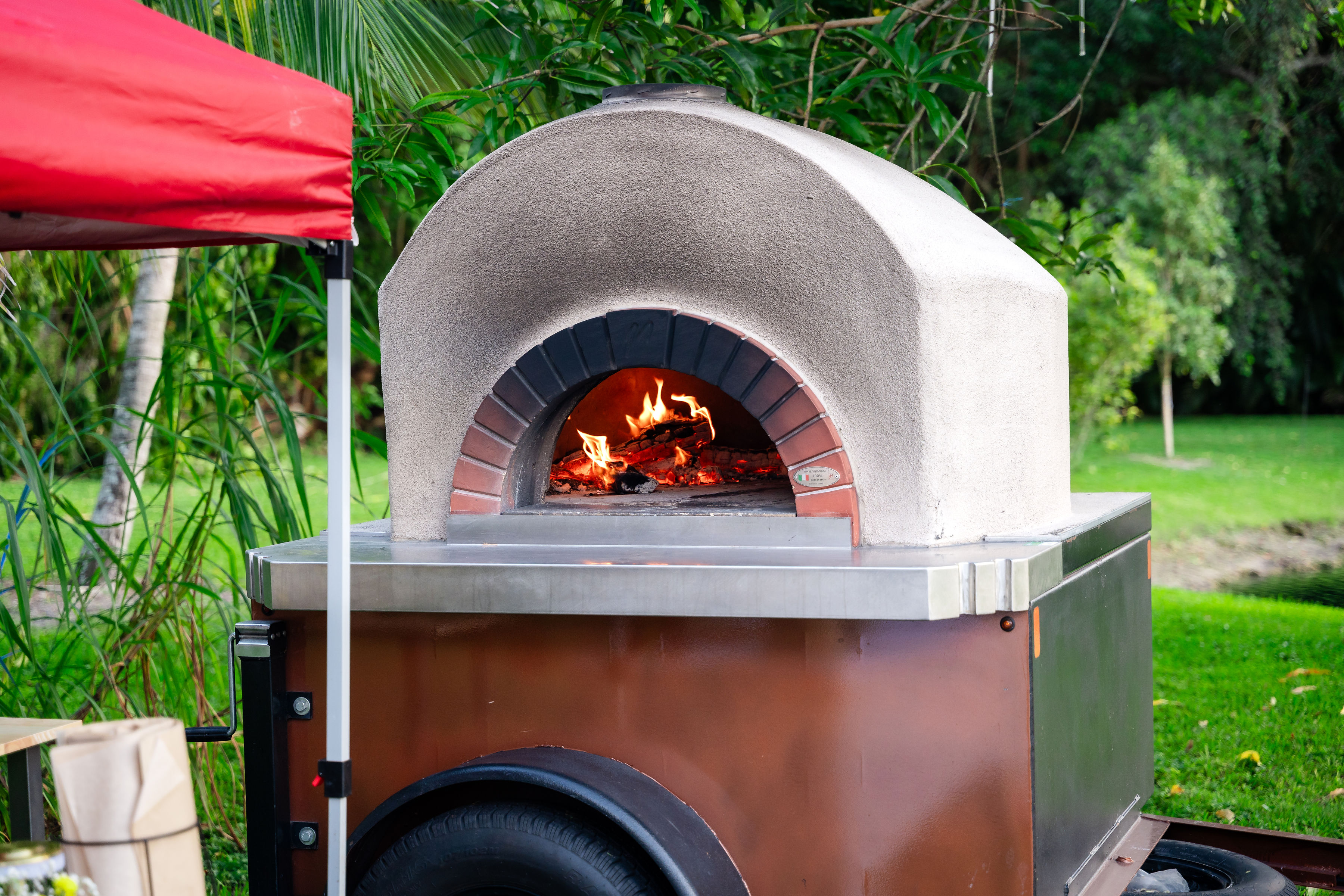 Wood-fired pizza oven outdoor catering station for estate quinceañera event at Saint Patrick Palace.