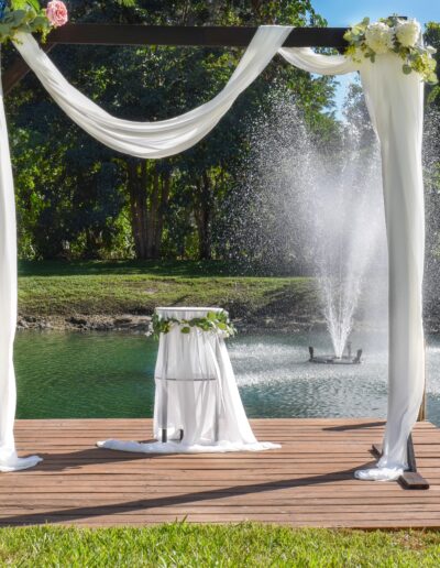Elegant lakeside wedding altar with white drapery and floral accents at Saint Patrick Palace.