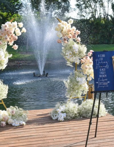Romantic dockside wedding with floral arch and fountain backdrop.