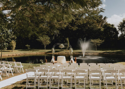 Romantic lakeside wedding ceremony with fountain backdrop and elegant white seating.
