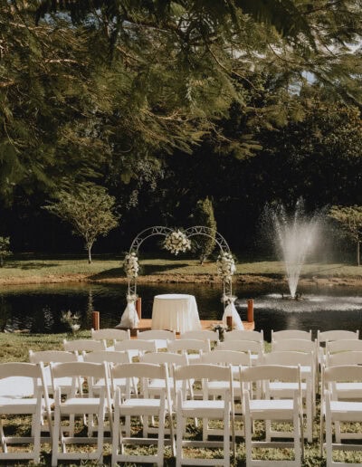 Romantic lakeside wedding ceremony with fountain backdrop and elegant white seating.