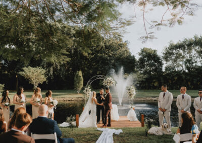 Romantic lakeside wedding with fountain backdrop and white floral arch at Saint Patrick Palace.