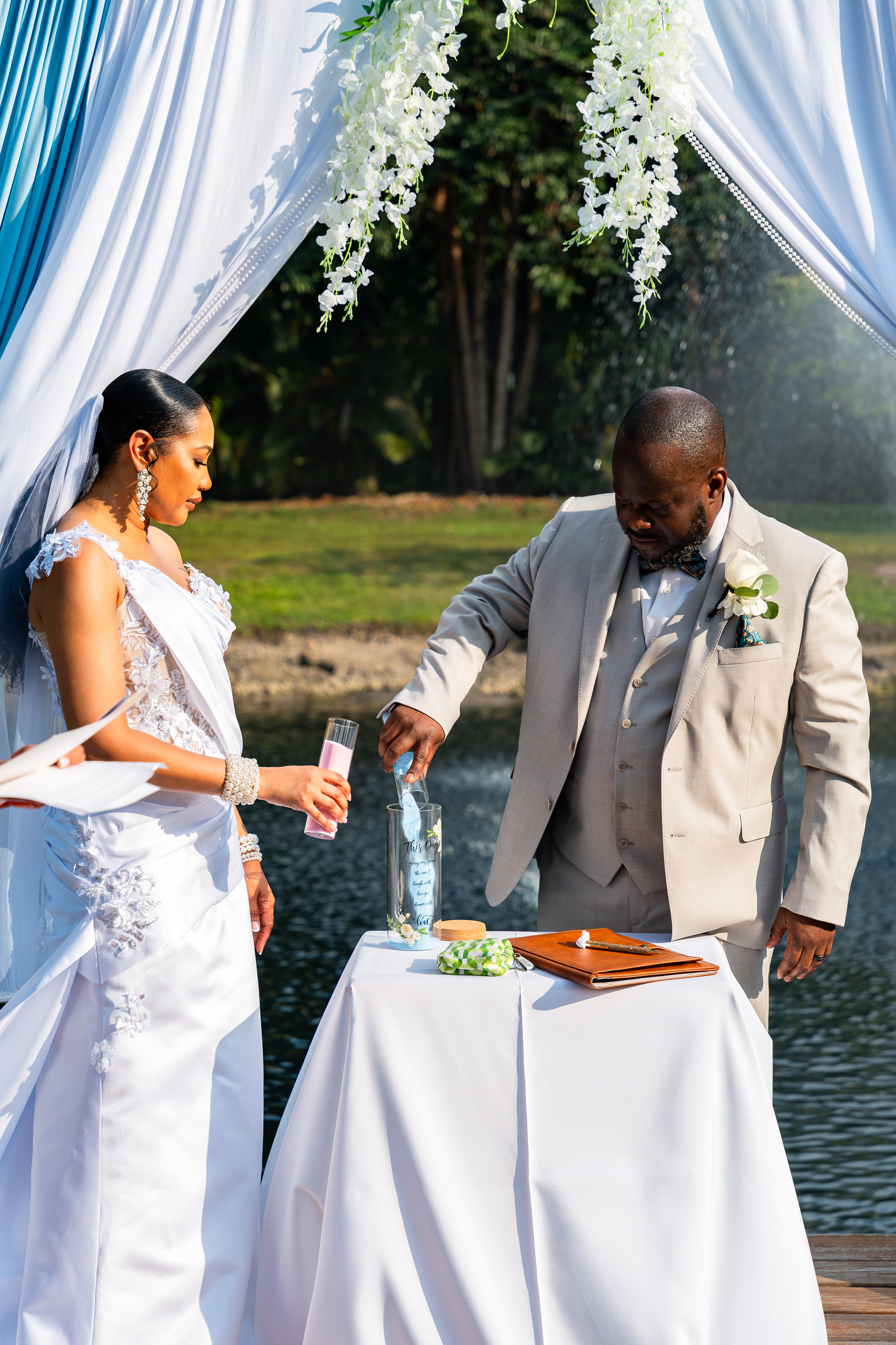 Bride and groom performing unity sand ceremony beside the pond at Saint Patrick Palace in South Florida.
