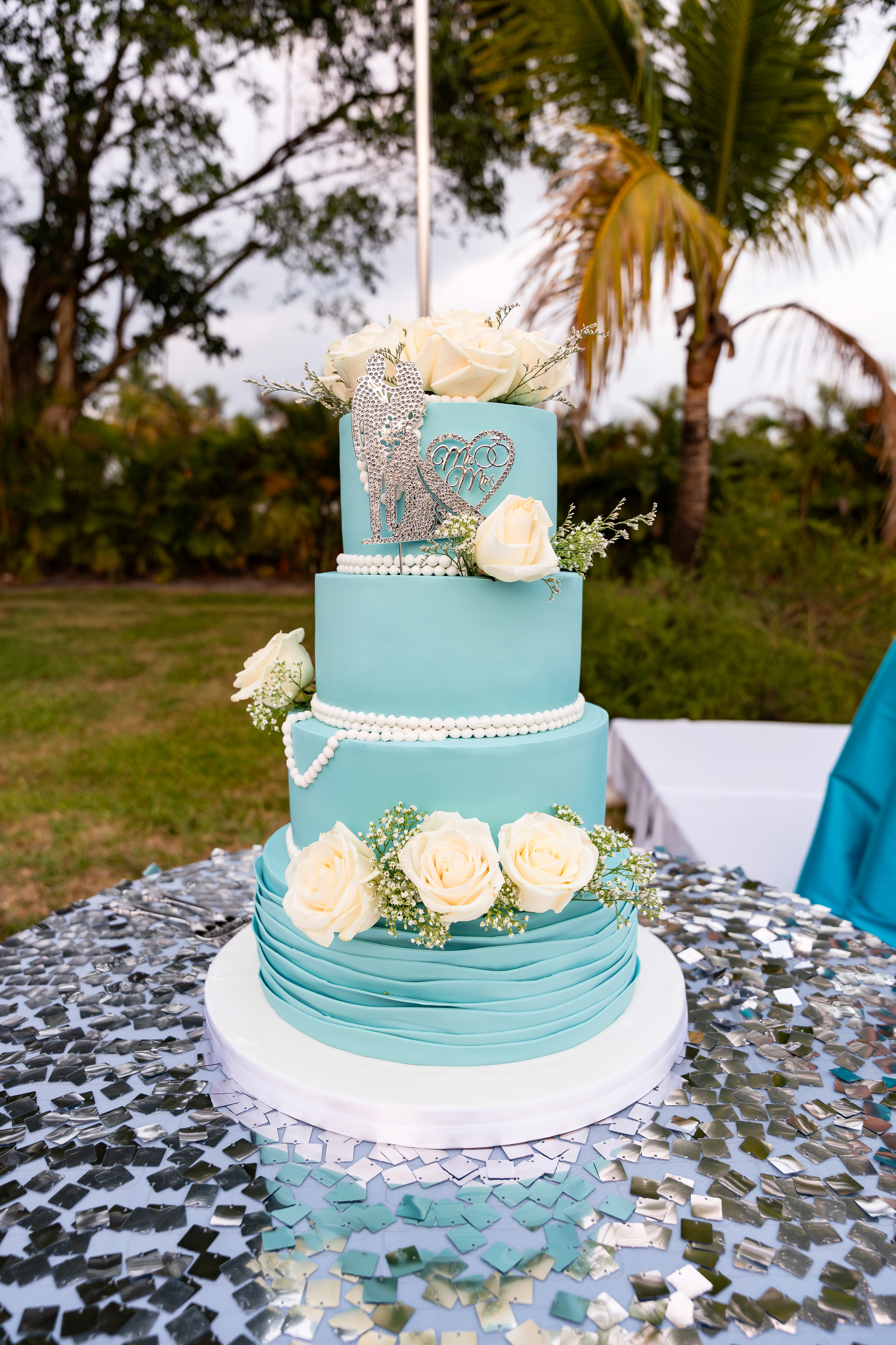 Aqua blue wedding cake decorated with white roses and pearls at a spring reception at Saint Patrick Palace.