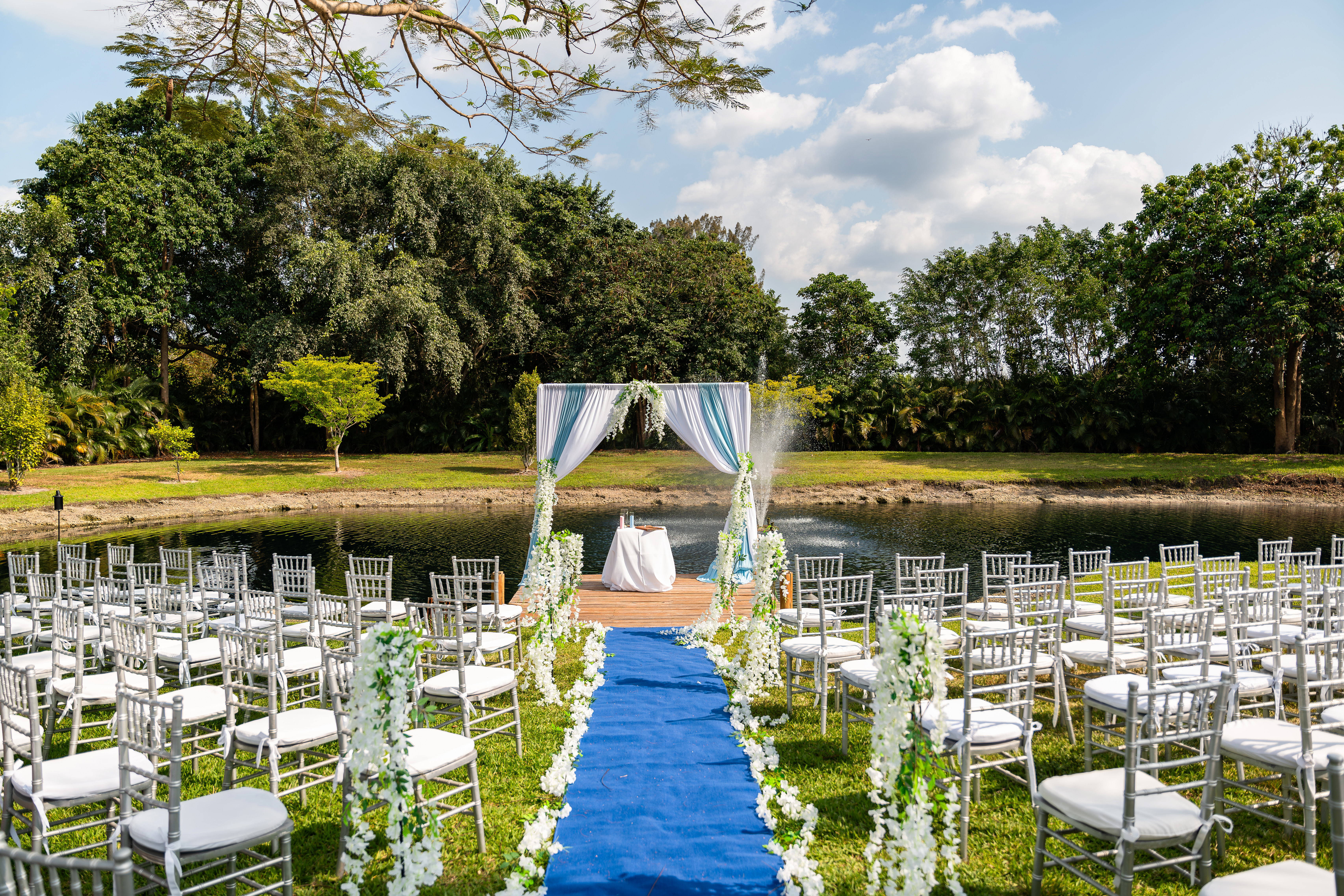 Elegant outdoor ceremony setup with teal and white draped arch overlooking the pond at Saint Patrick Palace.