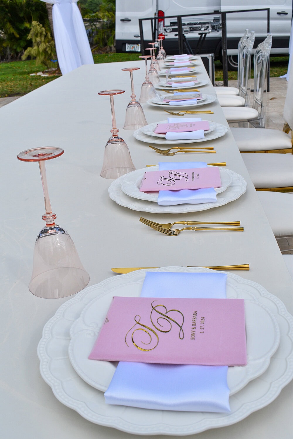 Long banquet table set with blush programs, gold flatware, and pink wine glasses at Saint Patrick Palace.