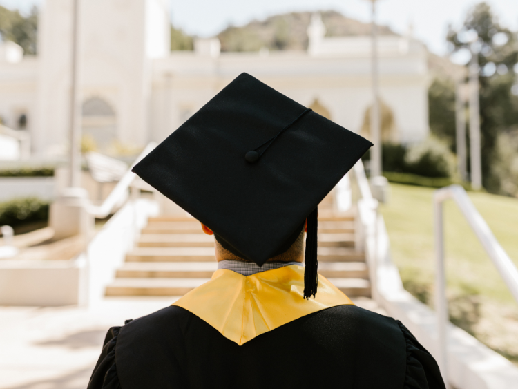 Graduate in cap and gown ready to celebrate with an Airbnb backyard party.