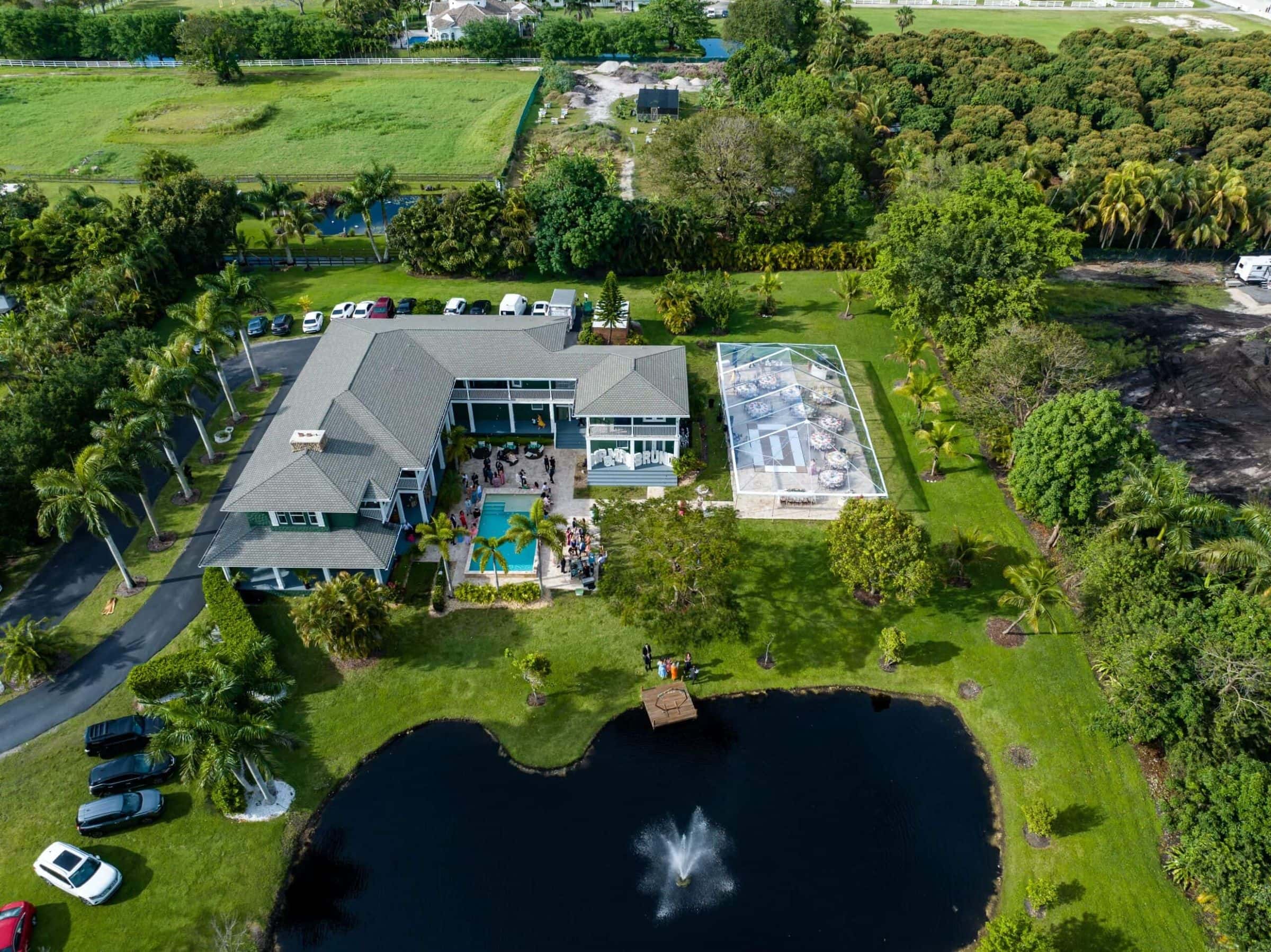 Aerial view of Saint Patrick Palace in Davie, showing the estate, pool, pond and tented event space.