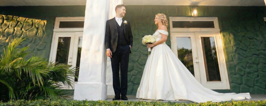 Bride and groom posing against white architectural columns and textured green stone wall at Saint Patrick Palace, illustrating the perfect backdrop for bold 2026 wedding color palettes