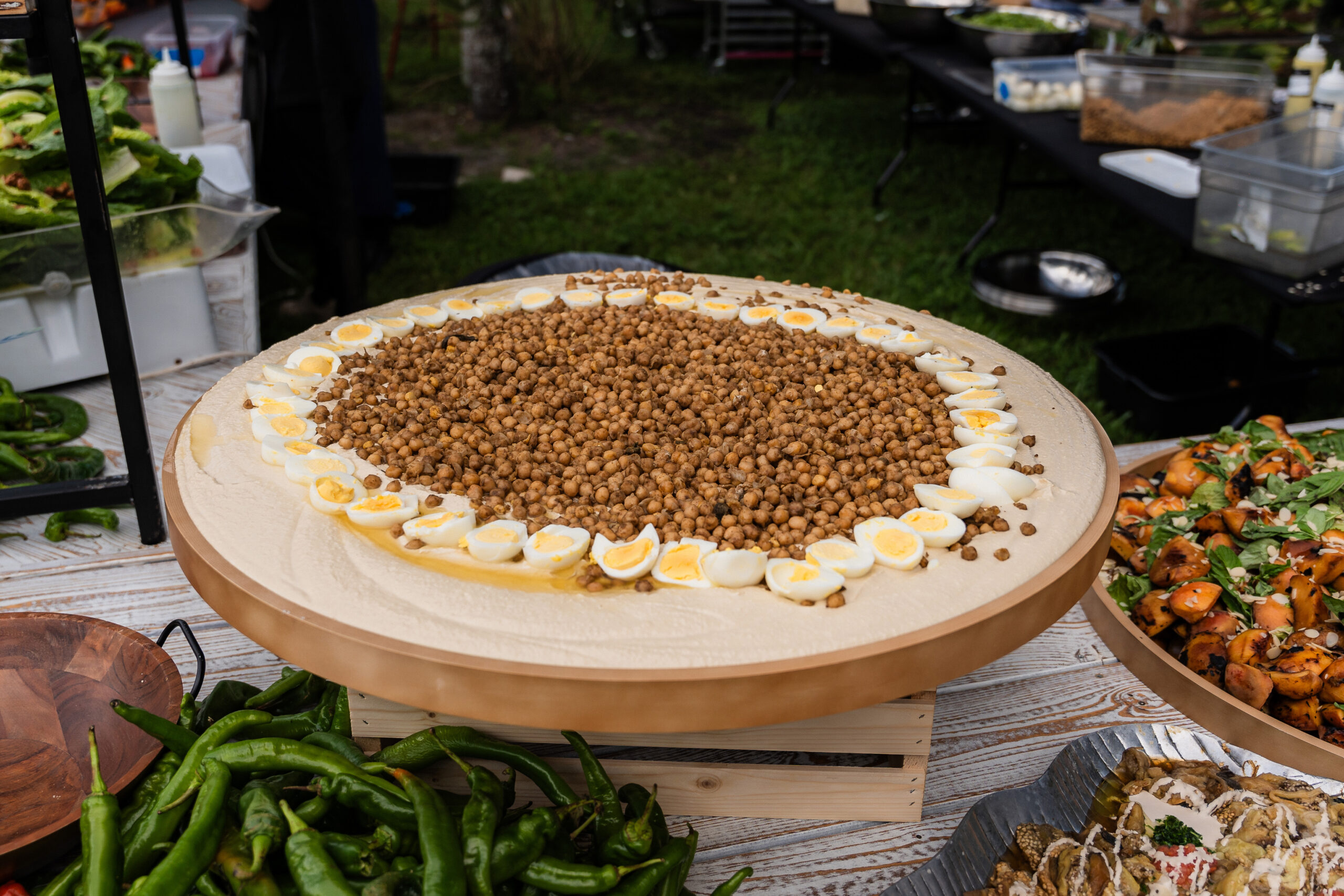 Large hummus platter with chickpeas and eggs, perfect for Bar/Bat Mitzvah catering and Middle Eastern event menus.