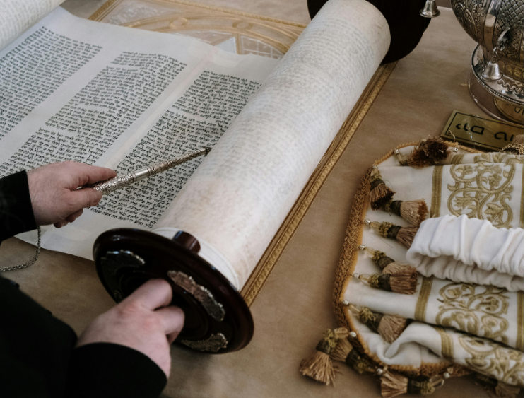 Torah scroll with yad pointer during Bar/Bat Mitzvah service, symbolizing tradition and Jewish heritage.